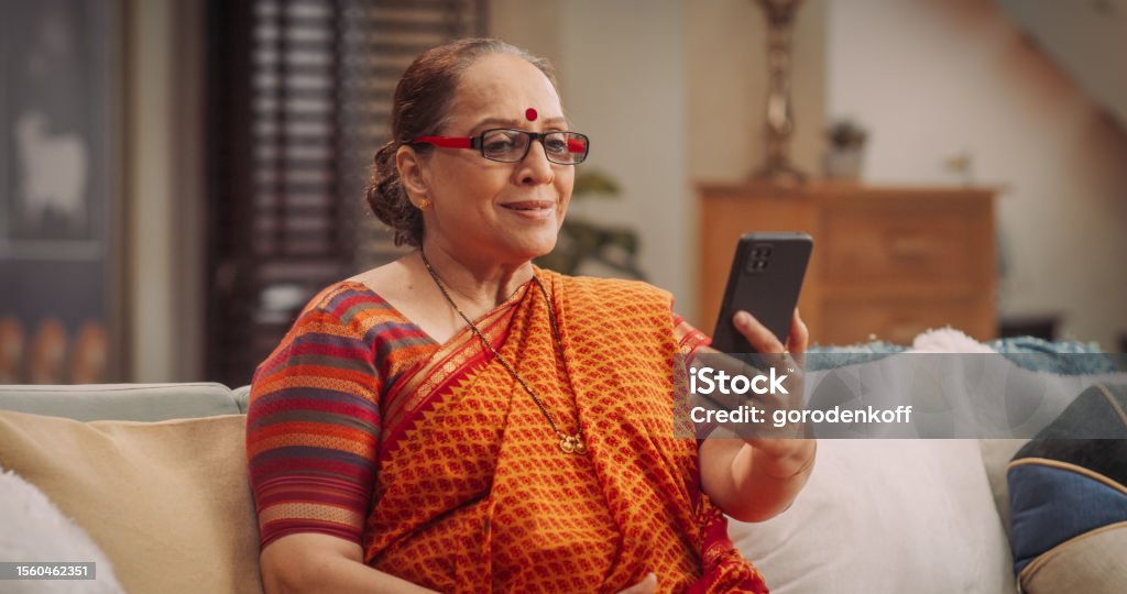 Elderly Indian Woman Using Video Call on Smartphone: Talking Long-Distance Friends, Smiling. Joyful Smiling Senior Lady Talking to Her Family, Relatives, Grandchildren. Closeup